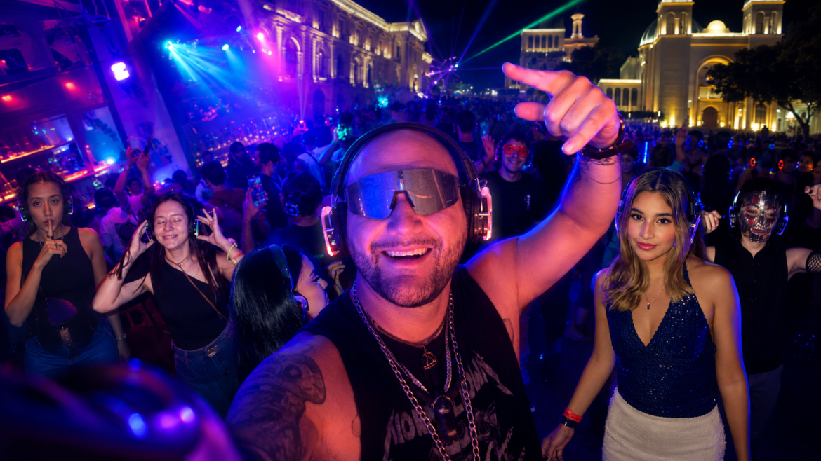 Silent Disco El Salvador llega al Centro Histórico | Pulsar Mix Radio FM Man in front with oversized headphones and a visor, smiling at a crowded neon-lit night party as others dance around him